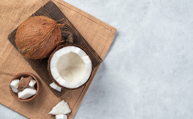 An open coconut on a wooden board on a light pink background.