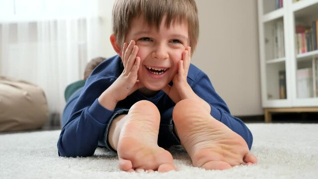 Portrait of happy smiling boy lying on mother's feet and looking in camera. Family having fun and playing together