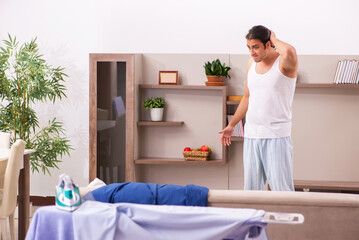 Young male employee ironing in the morning