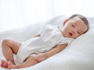 Close up adorable asian 3 months years old baby girl sleeping on white bed , newborn peace sleeping concept