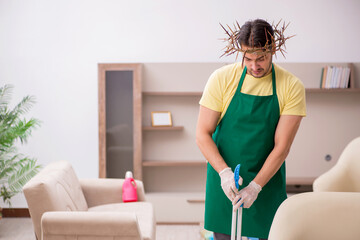 Young male contractor wearing prickly wreath on head cleaning th