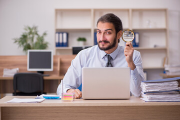 Young businessman employee holding loupe in auditing concept