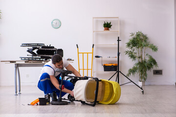 Young male repairer repairing perambulator indoors