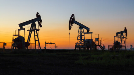 Three oil rigs on the background of the sunset. Silhouette of oil rigs. Oil Production.