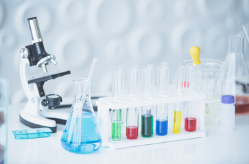 Microscope and colorful test tubes on table in Laboratory. Science chemistry concept. Blue tone