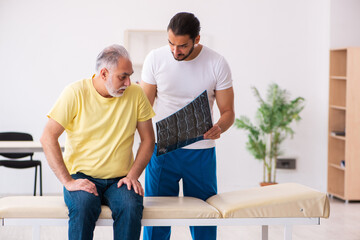 Old male patient visiting young male doctor chiropractor