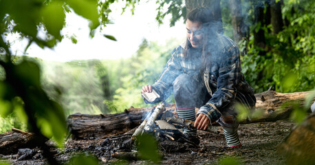 A girl on a hike in the woods prepares a fire.