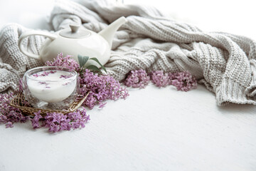 Spring home still life with a cup of milk and lilac flowers copy space.