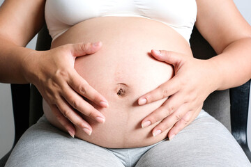 She have a baby. Woman is pregnant touching belly with love of mother and baby. Relationship during...