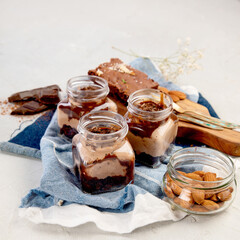 Trifles made with chocholate mousse and brownie on light gray background.