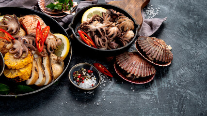 Grilled seafood variety with vegetables on dark background.