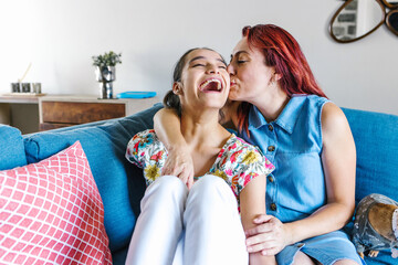 hispanic mother and her disabled daughter with cerebral palsy enjoying time together at home in disability concept in Latin America - obrazy, fototapety, plakaty