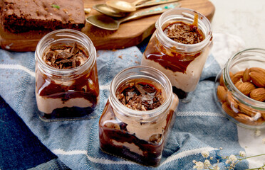 Trifles made with chocholate mousse and brownie on light gray background.