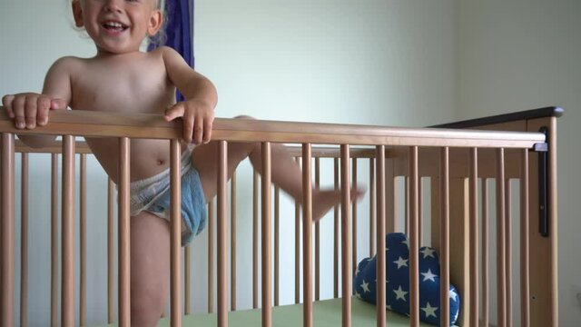 happy baby boy in diapers want to climb off his bed. Gimbal movement back