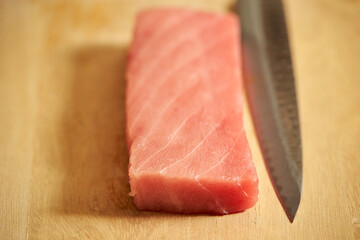 Sashimi knife on fresh tuna on cutting board