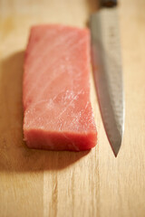 Sashimi knife on fresh tuna on cutting board
