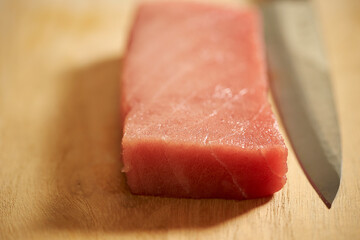 Sashimi knife on fresh tuna on cutting board