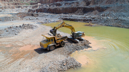 Mining industry. Crawler excavator loads mined ore into a mining dump truck.