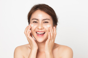 Asian woman looking happy applying cream on her face. Young female applying facial skincare cream. 