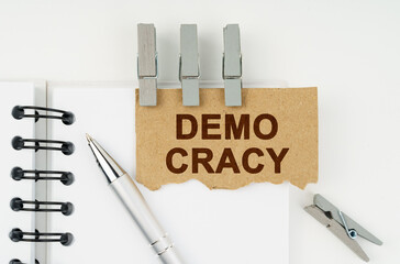 On a white background lies a notebook, a pen, clothespins and cardboard with the inscription - Demo...