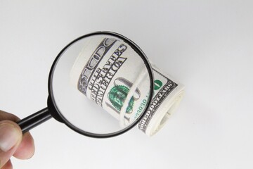 fingers holding a magnifying glass to find money