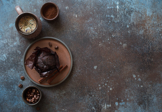 Cup of coffee, chocolate muffin and cinnamone sticks on dark stone background. Flat lay. Copy space