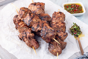 Grilled sirloin tips or beef meat skewers with chimichurri sauce, on wooden tray, horizontal