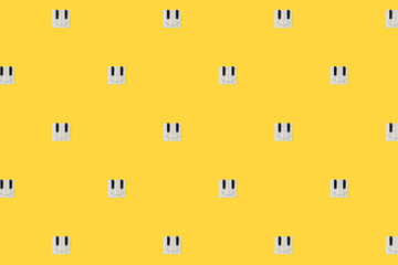 Creative, abstract happy face emoji icons texture with piano keys isolated on illuminating yellow background. Positive emotion music concept. Square emoticon pattern with copy space. Minimal flat lay.