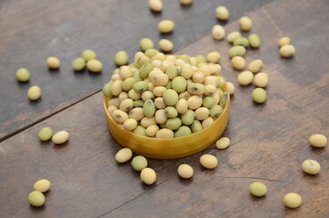closeup bunch the ripe green yellow soybean in the plastic bowl over out of focus wooden brown background.