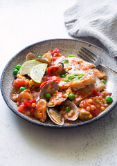 Fish fillet, mussels, vongoles, pasta ptitim stew in tomato sause close up