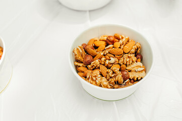 serving plate a mixture of nuts: almonds, hazelnuts, walnuts on light table in an open space. healthy summer raw snacks for a party. healthy lifestyle. selective fous