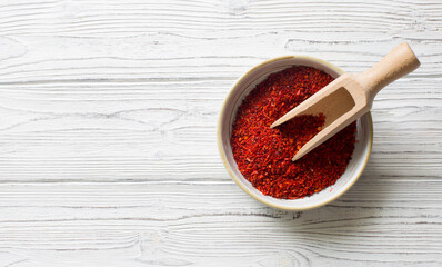 Paprika flakes in a bowl on white wooden background. Flat lay