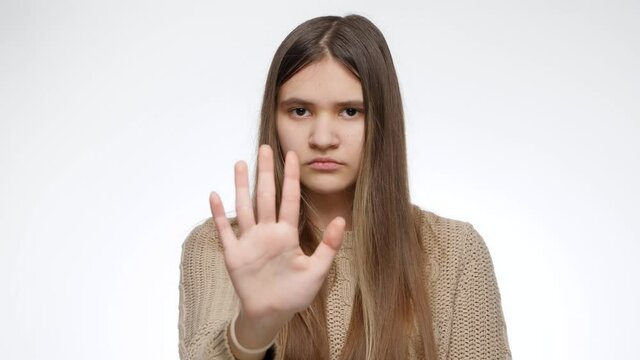 Stop or no sign. Girl showing refuse or deny gesture with hand over white studio background
