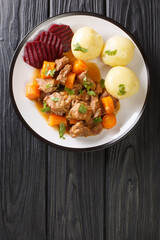 Beef stew with a side dish of boiled potatoes and pickled beets close-up in a plate on the table. vertical top view from above