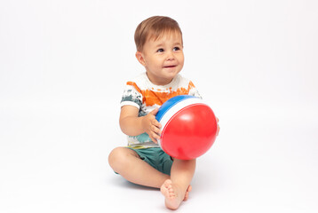 Adorable baby playing with a colorful beach ball, isolated on white
