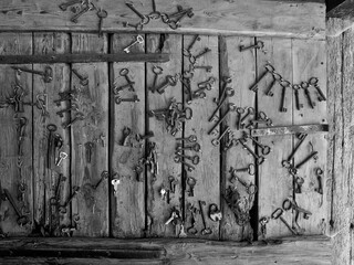 Old household and farm equipment, door keys, pitchforks, rakes, hoes, threshing machines, tube radios, wagon wheels, ladder carts in black and white photography.