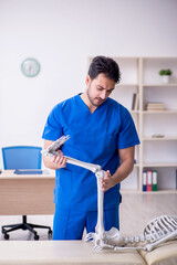 Young male doctor examining skeleton patient