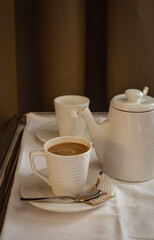 Coffee service for two at a hotel, pot, two cups and saucers, sugar and sweeteners on a tray with white linen.