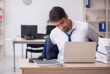 Fototapeta premium Young male employee unhappy with excessive work in the office