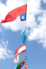 Flags on a background of a blue sky with clouds. Flags of different countries. Europe, Kazakhstan, Chile, Austria, Azerbaijan, Peru.