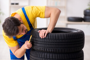 Young male garage worker with tyre at workshop © Elnur