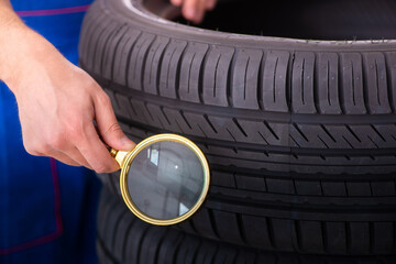 Young male garage worker with tyre at workshop