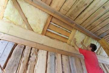 man installing glass wool insulation for new house construction