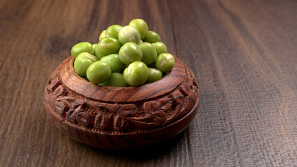 Fresh green peas in wooden bowl on wooden background.