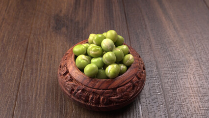 Fresh green peas in wooden bowl on wooden background.