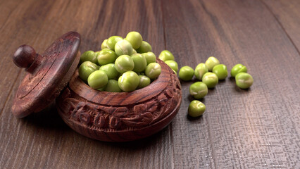 Fresh green peas in wooden bowl on wooden background.