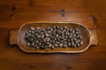 Raw in shell whole Pecan nuts in a wooden bowl on a wood table with a vintage nut cracker
