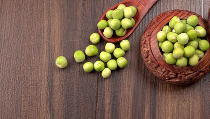 Fresh green peas in wooden bowl on wooden background.