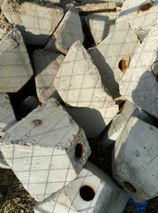 Cement pyramids for road signs with a hole for an iron pole are lying in a pile of building material