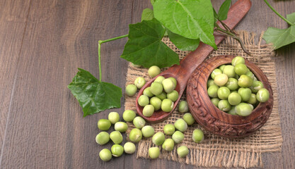 Fresh green peas in wooden bowl on wooden background.